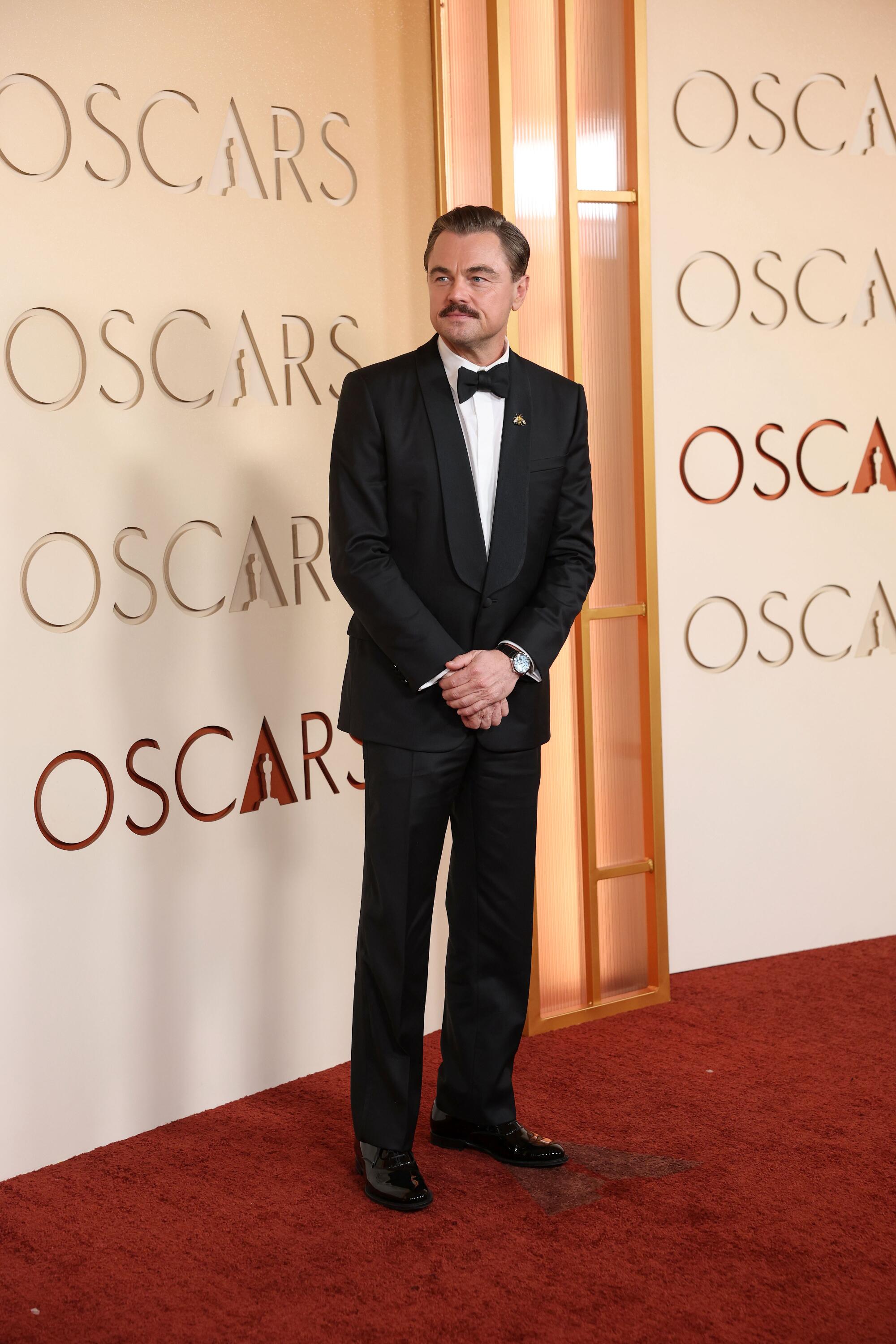 Leonardo DiCaprio, wearing a tux, poses on the red carpet. 