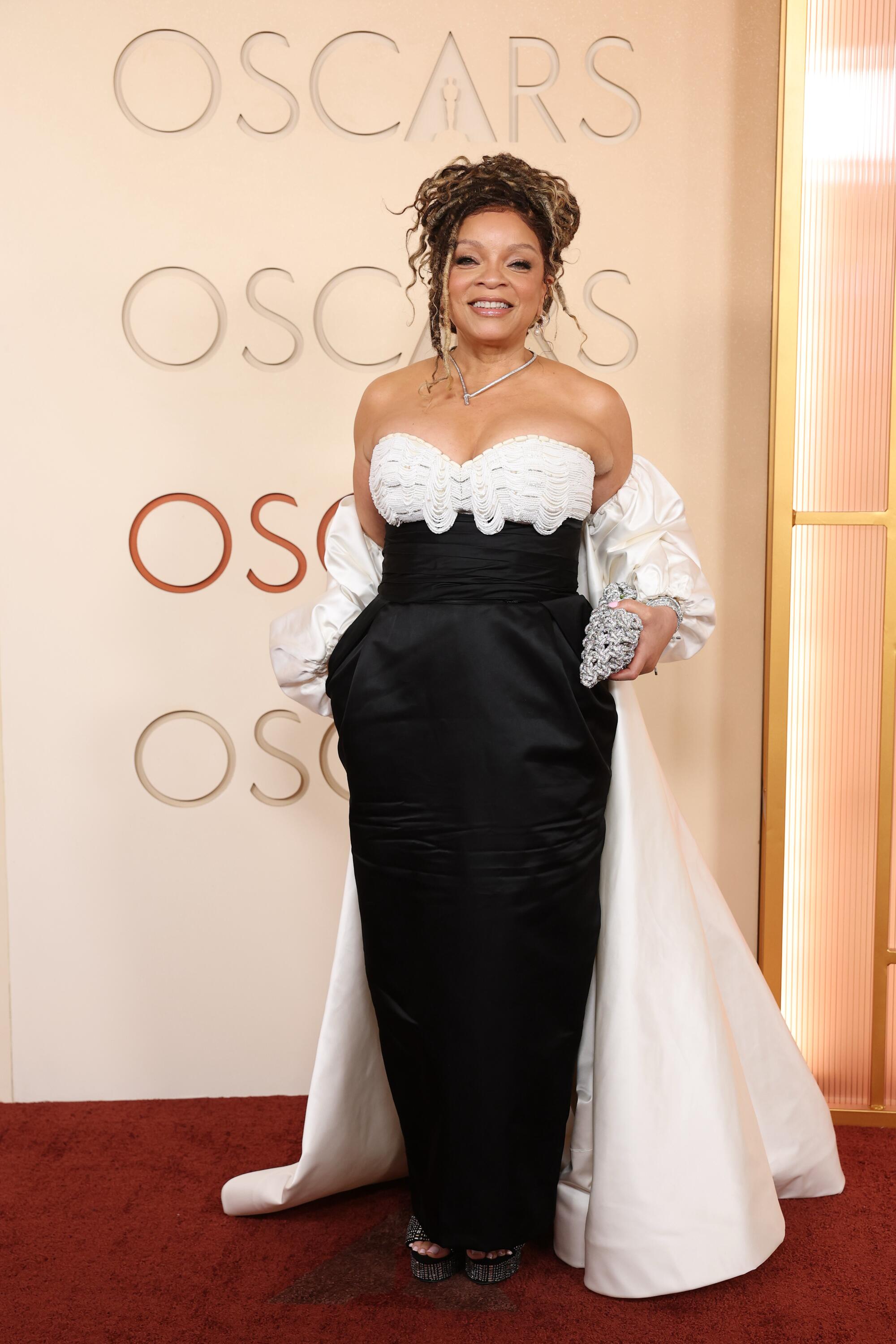 Ruth E. Carter, wearing a black gown with a white train, poses on the red carpet. 