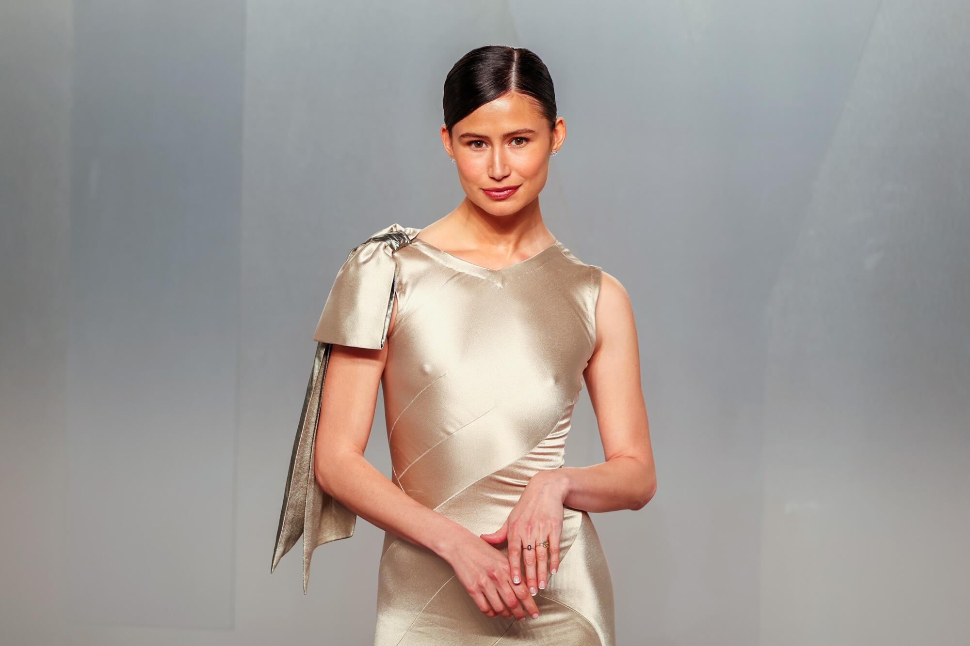 Delaney Rowe, wearing a Champagne dress, poses at the Vanity Fair Oscar Party red carpet. 