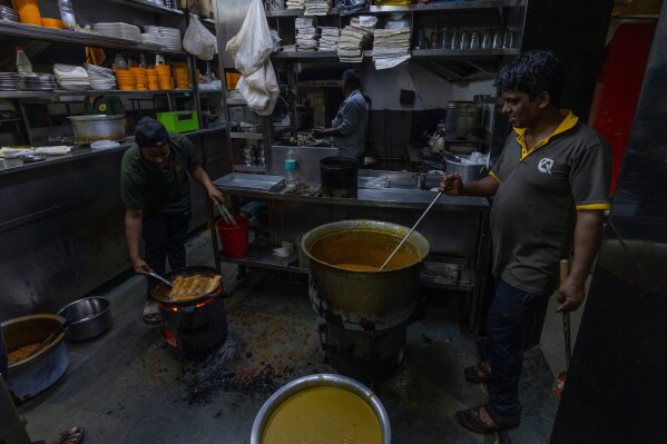 Cooks at a restaurant prepare meals over a charcoal stove following a shortage of liquefied petroleum gas in Mumbai, India, Wednesday, March 11, 2026. (AP Photo/Rafiq Maqbool)