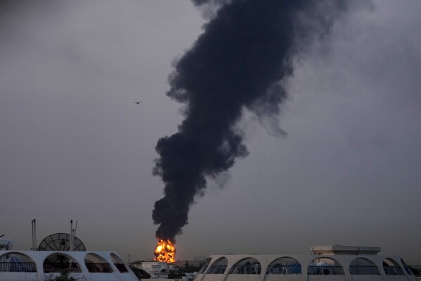 Fire and plumes of smoke rise after a drone struck a fuel tank forcing the temporary suspension of flights. near Dubai International Airport, in United Arab Emirates, early Monday, March 16, 2026. (AP Photo)