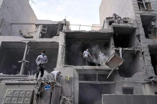 Volunteers clean debris from a residential building damaged when a nearby police station was hit Friday in a U.S.-Israeli strike in Tehran, Iran, Sunday, March 15, 2026. (AP Photo/Vahid Salemi)