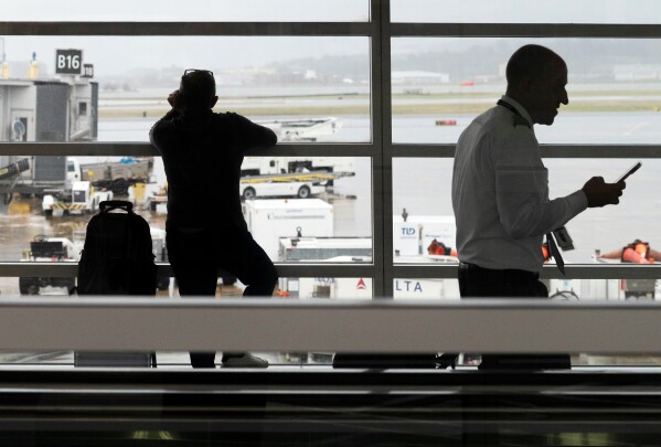 People wait in a departure terminal at Ronald Reagan National Airport, in Arlington, Va., Monday, March 16, 2026. (AP Photo/Cliff Owen)