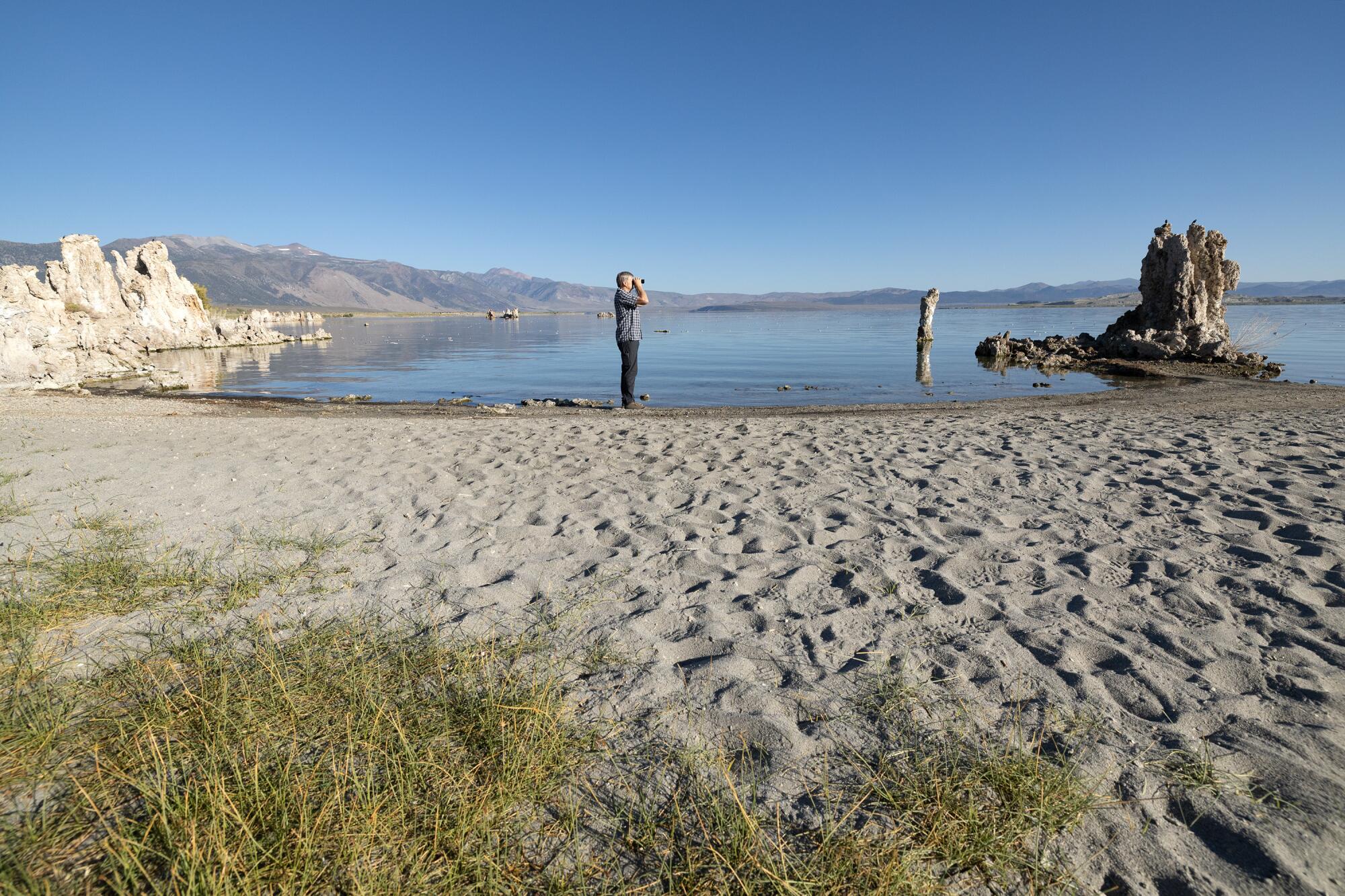 A man peers through binoculars at Mono Lake's South Tufa. 
