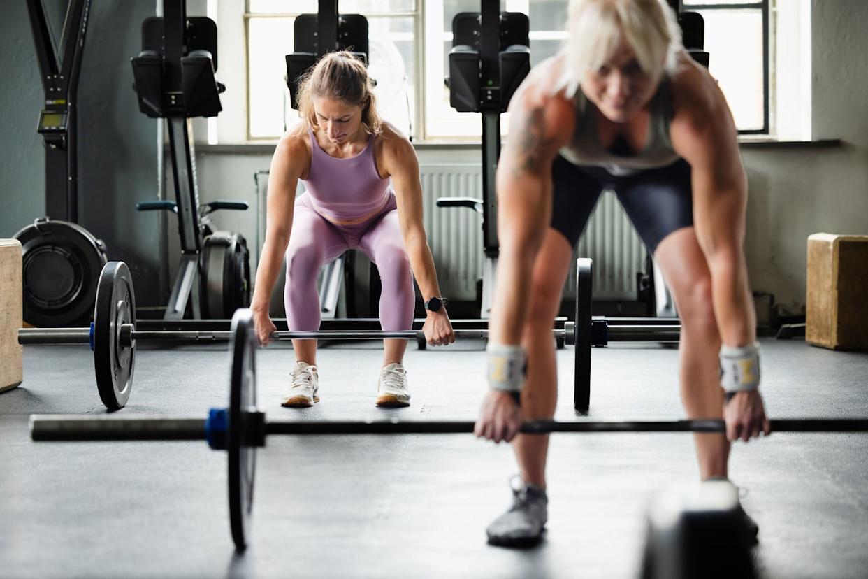 female cross training athletes preparing for deadlift exercise in gym