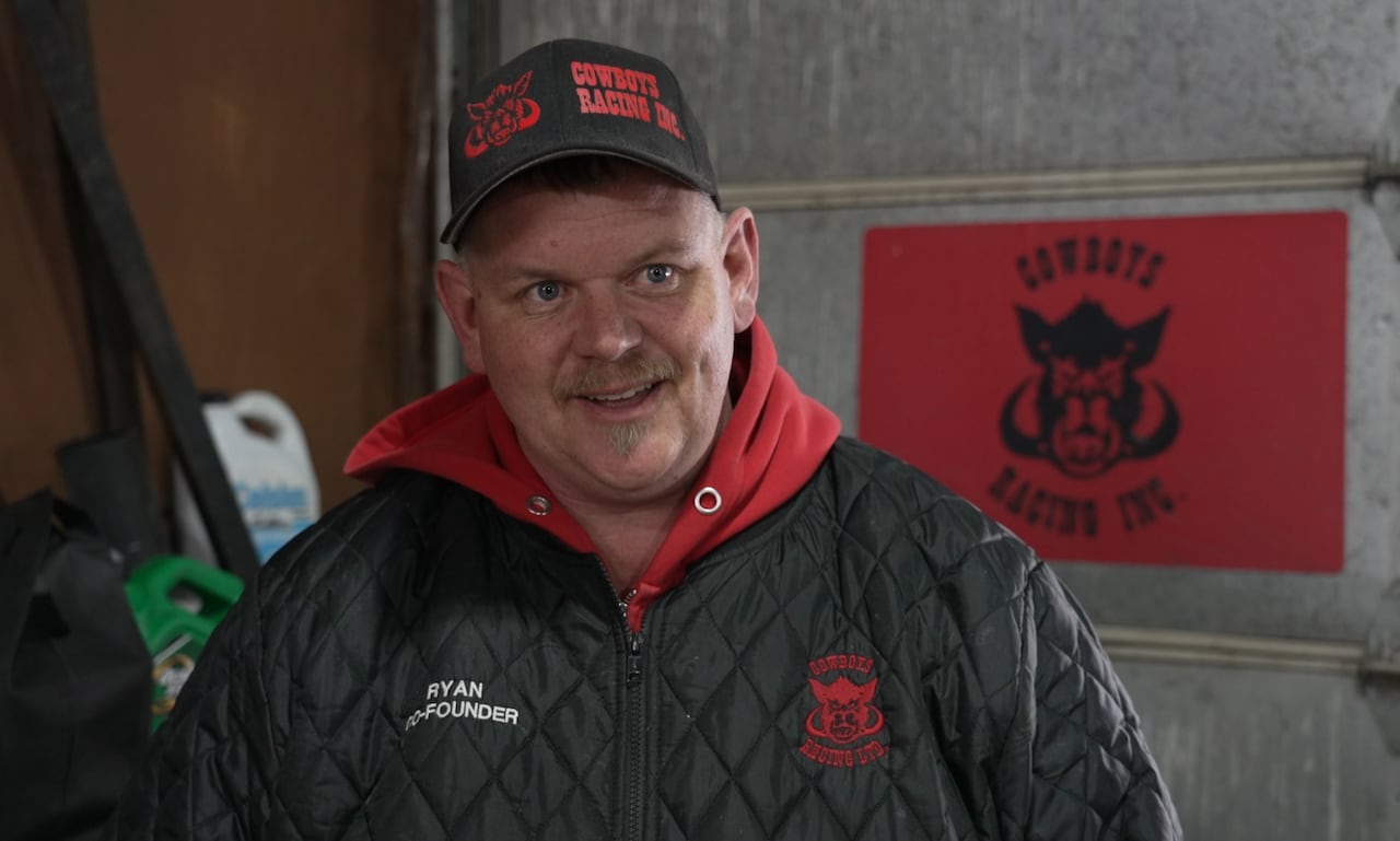 A man in a freezer jacket smiles at the camera