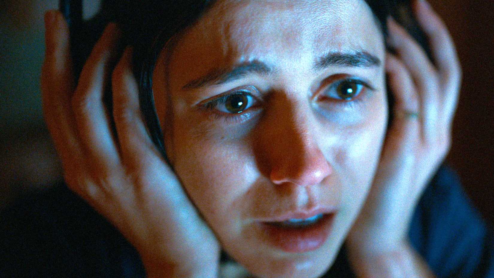 Nina Kiri's Evy looking worried while holding the headphones on her head in Undertone