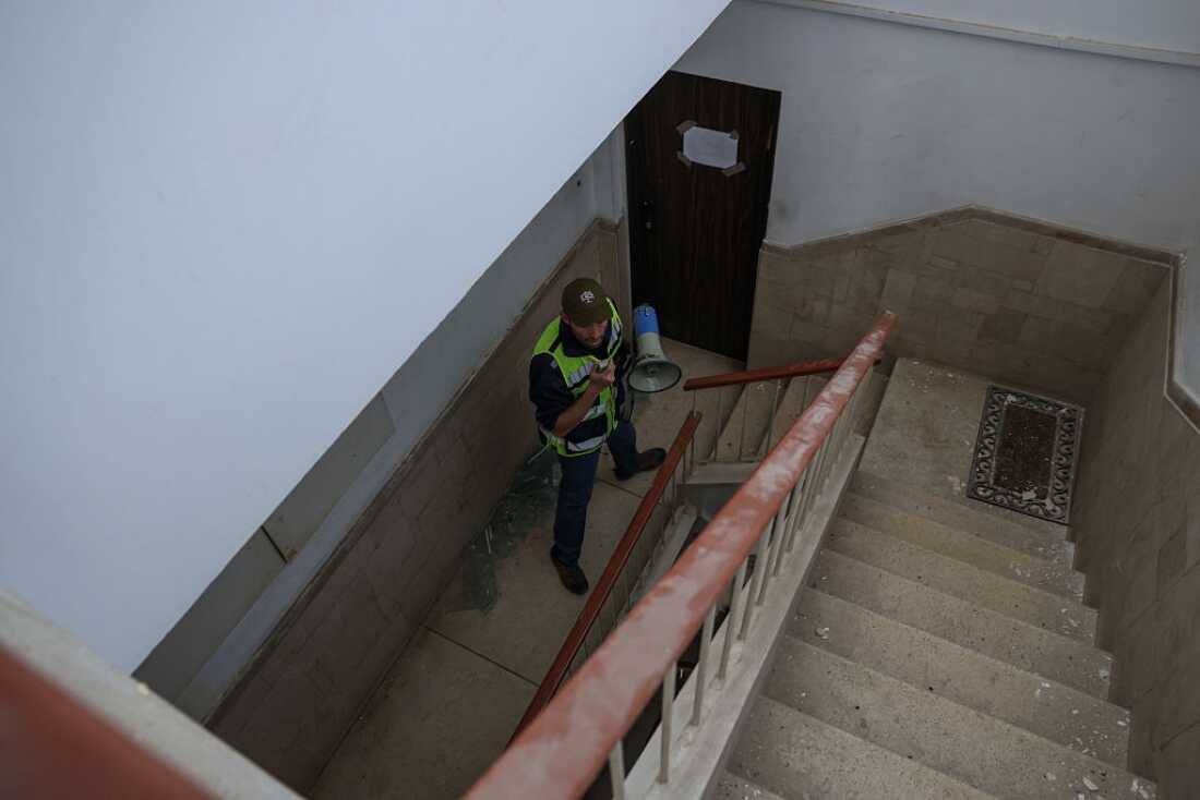 An Israeli emergency service worker urges residents to leave a building at the site of an Iranian missile strike in Tel Aviv on March 24, 2026.