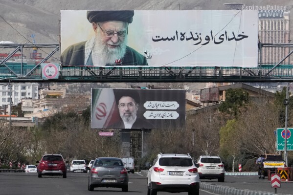 Vehicles drive under billboards showing portraits of the late Iranian Supreme Leader Ayatollah Ali Khamenei, foreground, and his son Ayatollah Mojtaba Khamenei, the successor to him, along a highway in Tehran, Iran, Tuesday, March 24, 2026. (AP Photo/Vahid Salemi)