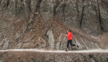 woman running on rocky singltrack in red jacket
