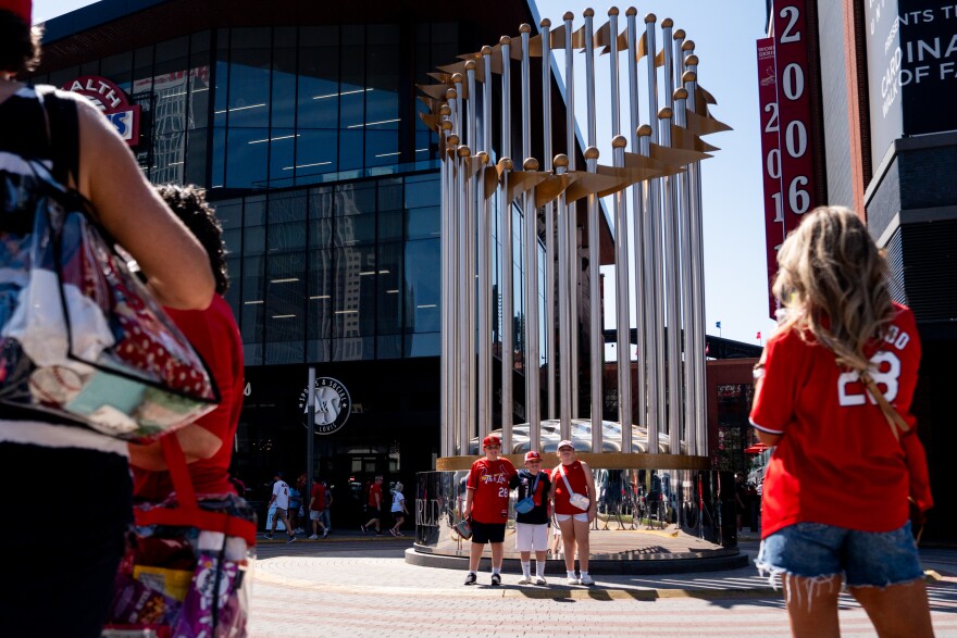 St. Louis Cardinals fans take photos in front of a giant replica of the World Series trophy during MLB Opening Day festivities on Thursday, March 26, 2026, in downtown St. Louis.