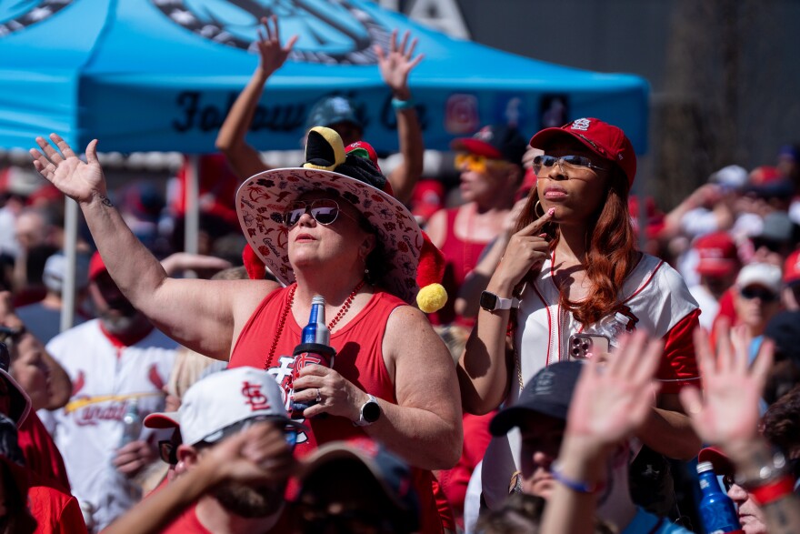 Mickey McPherson, of Swansea, left, raises her arms during MLB Opening Day festivities at Ballpark Village on Thursday, March 26, 2026, in downtown St. Louis.