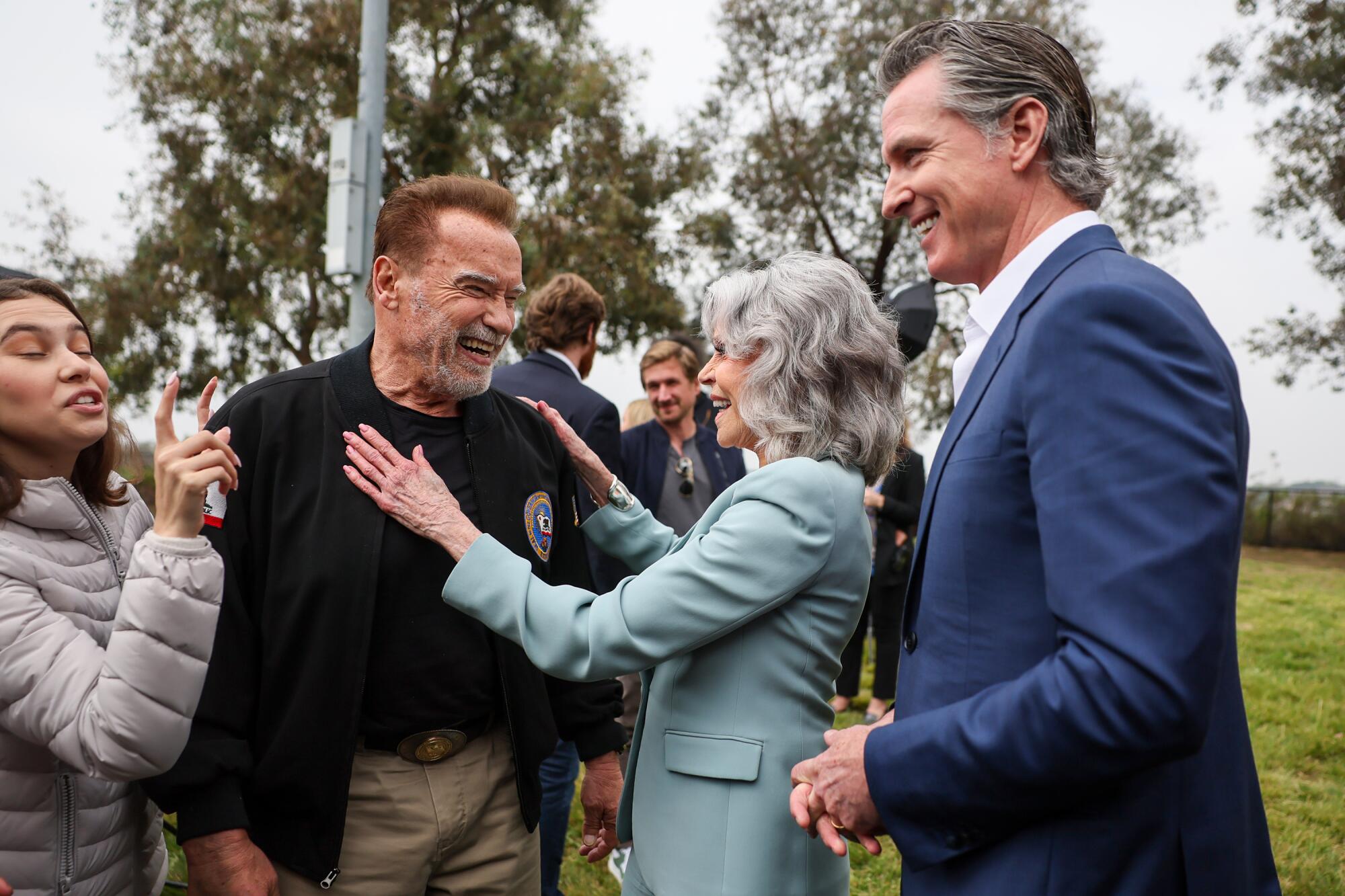 Gov. Gavin Newsom looks on as Jane Fonda hugs former Gov. Arnold Schwarzenegger in 2024.