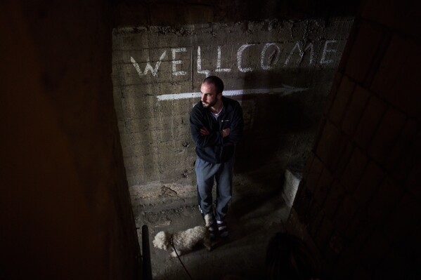 A man takes cover in a bomb shelter underneath a residential building as air raid sirens warn of incoming missile strikes from Iran in Ramat Gan, Israel, Sunday, March 22, 2026. (AP Photo/Oded Balilty)