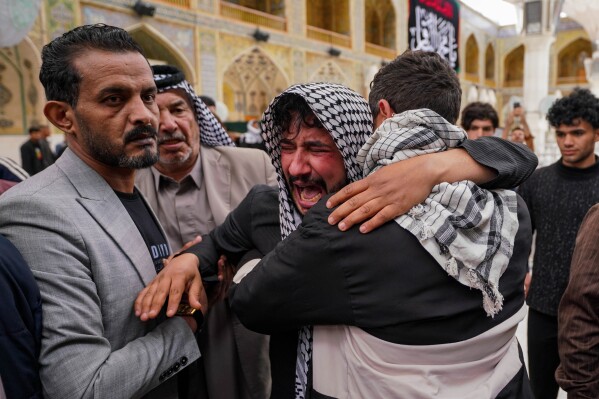 Relatives grieve for an Iraqi soldier, who was killed in a Wednesday strike, at a military clinic in western Iraq's Anbar province, during a procession inside the shrine of Imam Ali in Najaf, Iraq, Thursday, March 26, 2026. (AP Photo/Anmar Khalil)