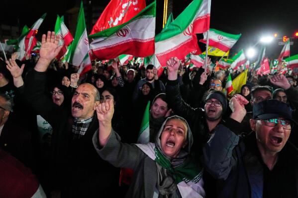 Pro-government supporters chant slogans and wave Iranian flags during a rally in a square in western Tehran, Iran, Wednesday, March 25, 2026. (AP Photo/Vahid Salemi)