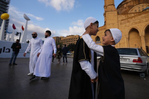 Two boys wearing new clothes for Eid greet each other outside the Mohammad Al-Amin Mosque during Eid al-Fitr celebrations in Beirut, Lebanon, Friday, March 20, 2026. (AP Photo/Hassan Ammar)