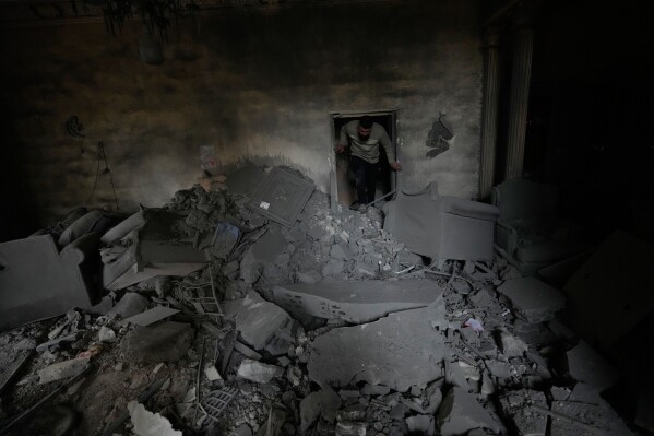 A man checks his damaged apartment at the site of a destroyed building hit in an Israeli airstrike in the southern port city of Tyre, Lebanon, Thursday, March 26, 2026. (AP Photo/Hussein Malla)