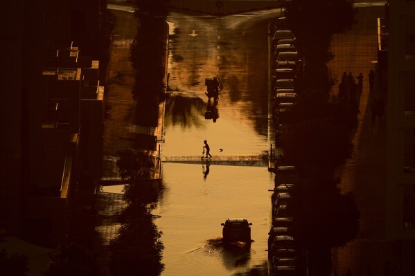 A boy crosses a street filled with rain water in Sharjah, United Arab Emirates, Monday, March 23, 2026. (AP Photo)