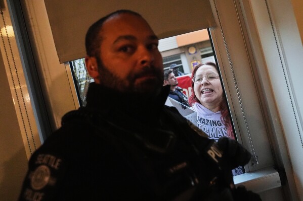 A protester yells after being removed from the building by Seattle Police before a bill-signing event with Washington Gov. Bob Ferguson regarding limiting facial coverings on law enforcement officers and making it a crime to impersonate a peace officer, Thursday, March 19, 2026, in Seattle. (AP Photo/Lindsey Wasson)
