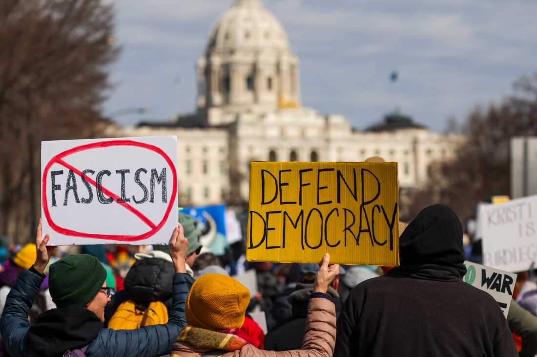Demonstrators hold signs while marching towards the Minnesota State Capitol during a No Kings protest in St. Paul on Saturday.