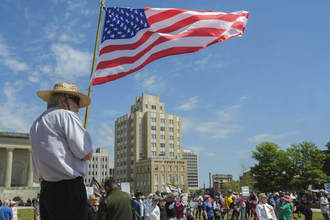 Lindsay Holliday waves an American flag in Rosa Parks Square in Macon, Ga. the site of the No Kings rally in the city on March 28, 2026. The rally was calm and lasted for about two hours before a small group of anti-ICE protesters objecting to Bibb County Sheriff David Davis’ invitation to speak shouted him down before he could take the microphone, effectively shutting the rally down.
