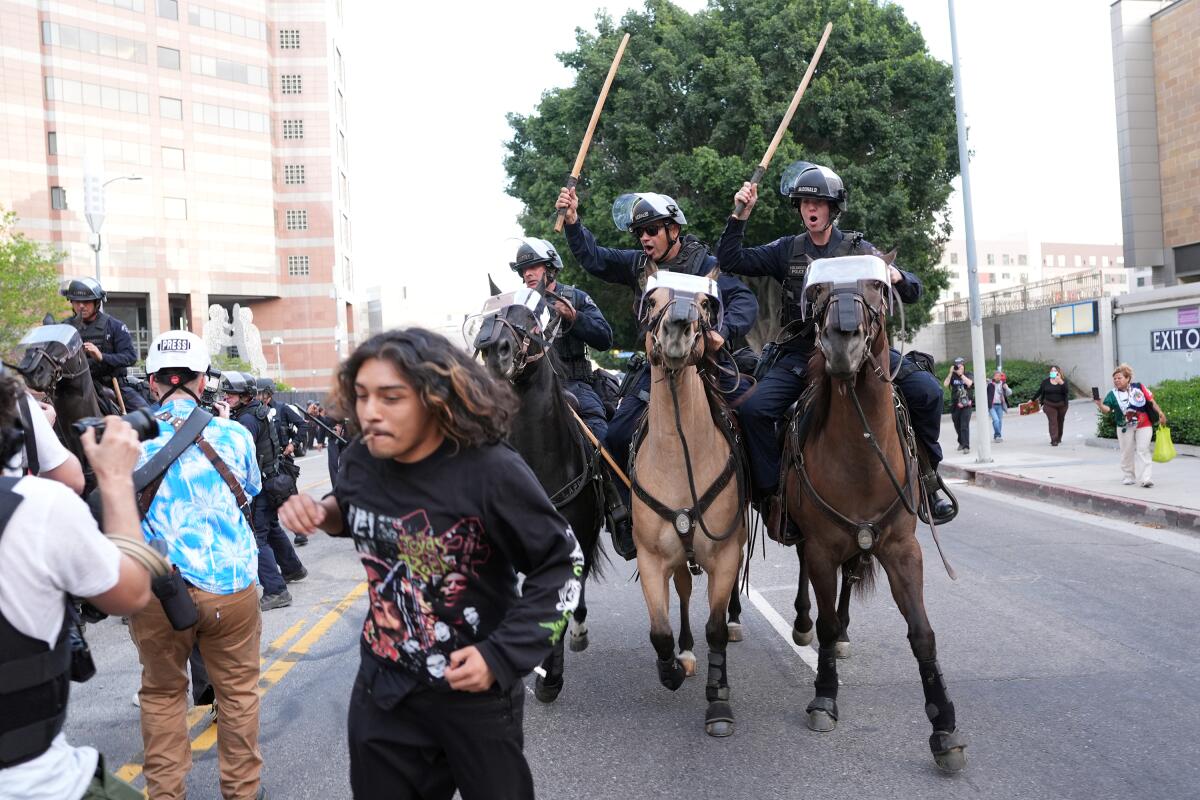 A man is chased by LAPD officers on horseback.