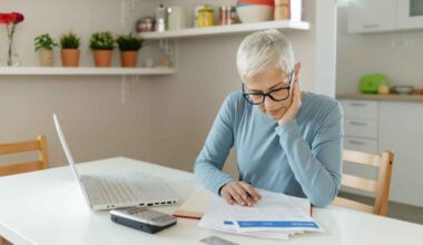 A woman puts her hand on her face as she looks at paperwork.