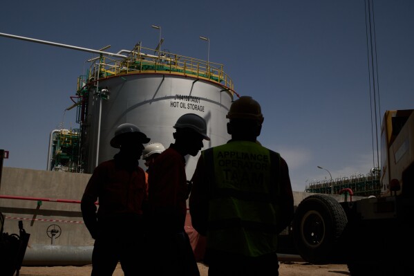 Workers stand in an area at a degassing station in Zubair oil field, whose operations have being reduced due to the Mideast war triggered by the U.S. and Israeli attacks on Iran, near Basra, Iraq, Saturday, March 28, 2026. (AP Photo/Leo Correa)