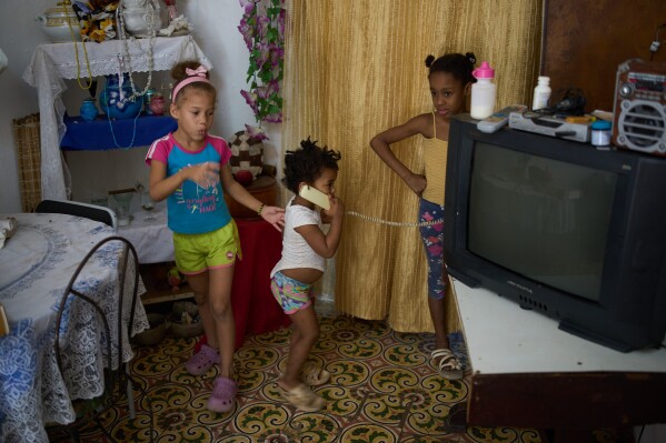 Edianet, left, and her sister Seinet, center, play with a friend at their home in Havana, Cuba, Wednesday, March 25, 2026. (AP Photo/Ramon Espinosa)