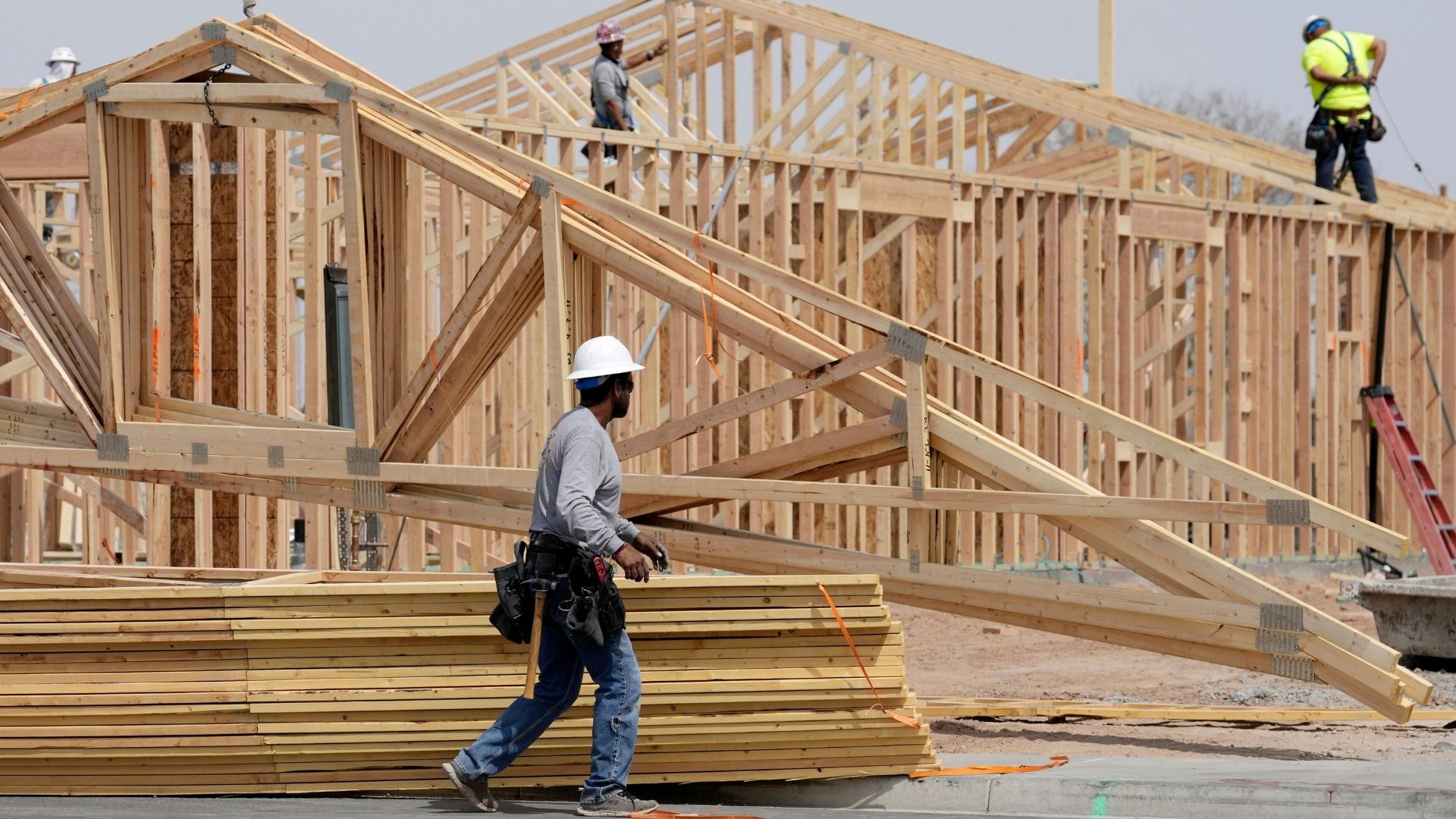 Construction workers install a lumber roof at a new home build Tuesday, April 1, 2025, in Laveen, Ariz.