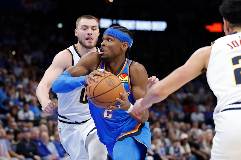 Mar 9, 2026; Oklahoma City, Oklahoma, USA; Oklahoma City Thunder guard Shai Gilgeous-Alexander (2) drives between Denver Nuggets guard Christian Braun (0) and forward Spencer Jones (21) during the second half at Paycom Center. Mandatory Credit: Alonzo Adams-Imagn Images