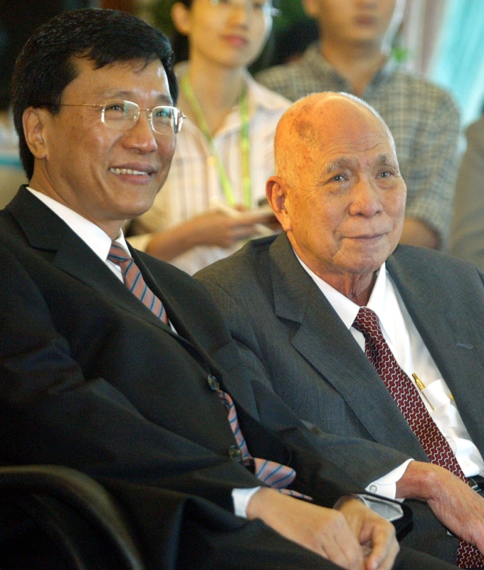 Malaysian rags-to-riches tycoon Lim Goh Tong (R) smiles as he sits next to his second son, Kok Thay, at their office in Kuala Lumpur on December 31, 2003. Photo by Reuters