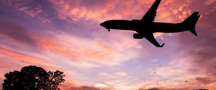 A plan flying in the evening against a purple sky