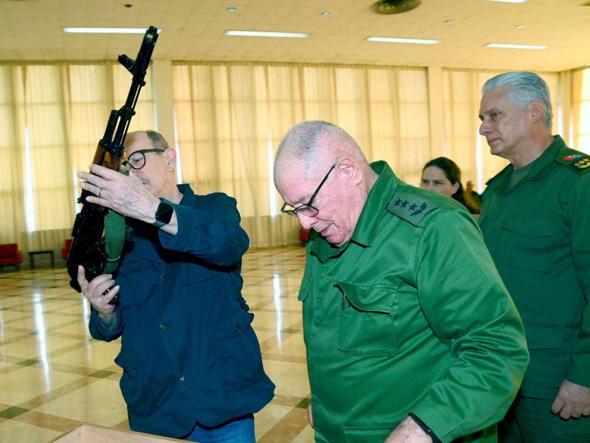 Cuban folk singer Silvio Rodriguez, standing near Cuban President Miguel Diaz-Canel, is presented with an AKM war rifle and a ceremonial replica by Minister of the Revolutionary Armed Forces Army Corps General Alvaro Lopez.