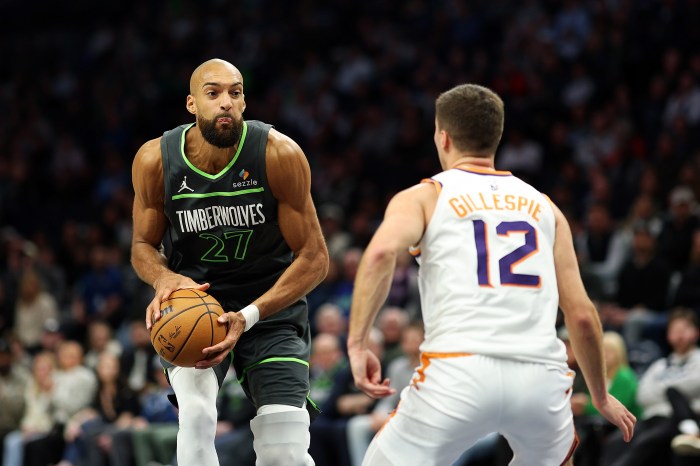 Rudy Gobert holds the ball as a defender guards him.