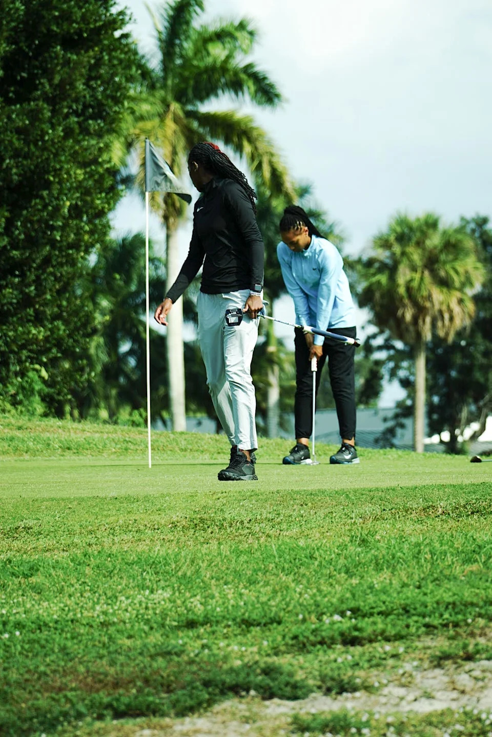 two individuals playing golf on a green course