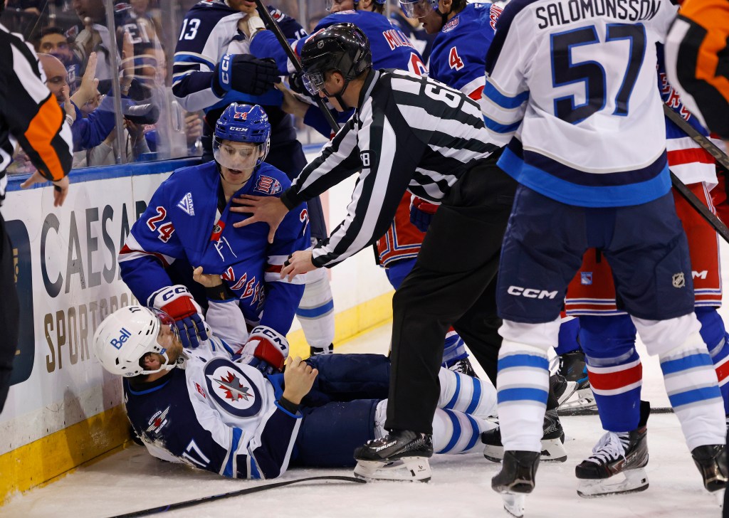 New York Rangers player Tye Kartye and Winnipeg Jets player Adam Lowry scuffle on the ice, separated by a referee.