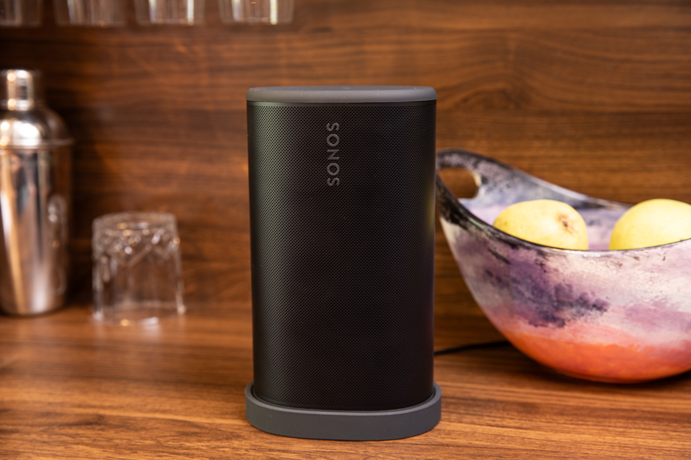 The Sonos Play speaker on its charging base with a bowl of fruit and some cocktail accessories in the background.
