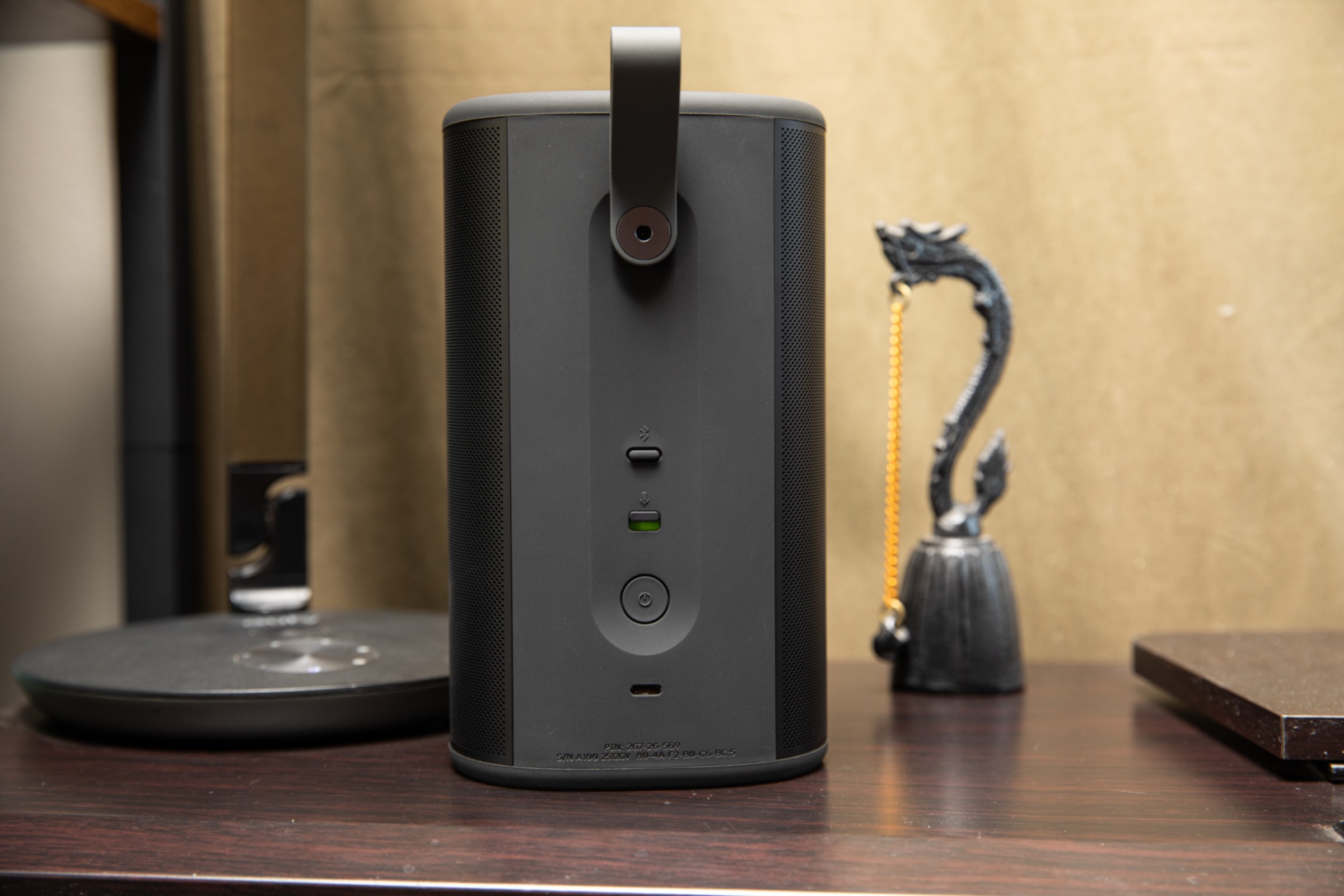 The back of the Sonos Play on a wooden surface with a lamp and bell in the background.