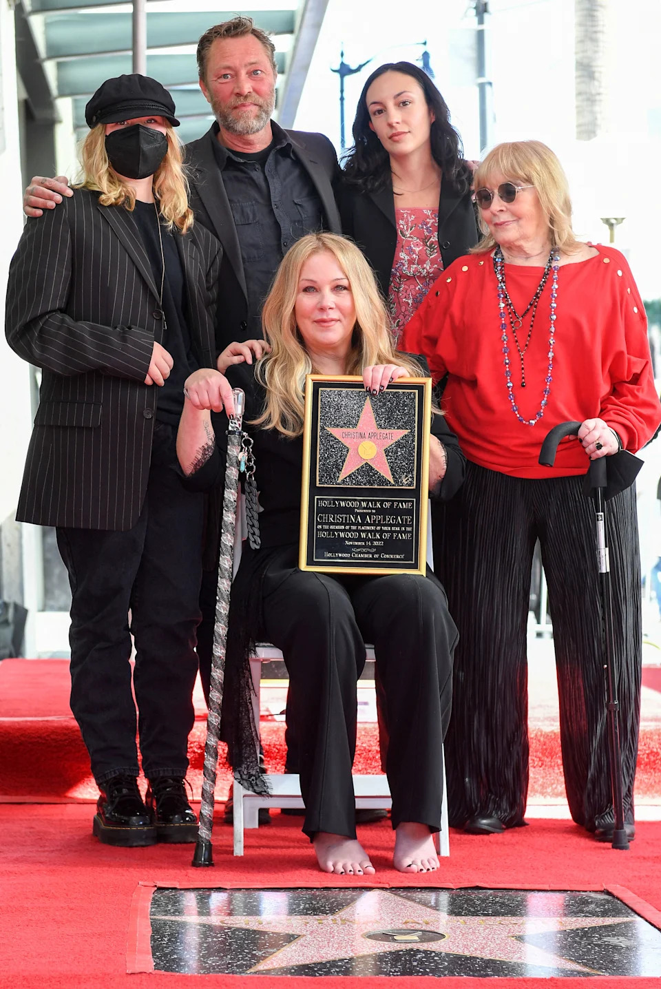 Barefoot, Applegate sits in a chair on the Hollywood Walk of Fame beside her newly unveiled star, surrounded by family members 