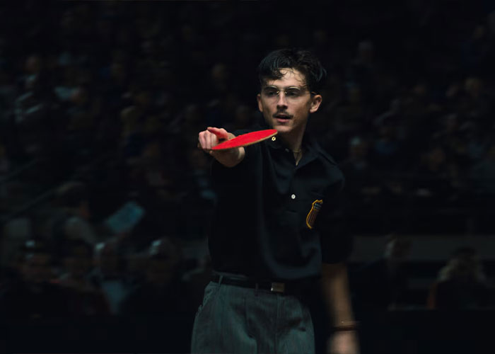 Timothée Chalamet in dark outfit playing table tennis, highlighting Academy insider claims on his Oscar chances.