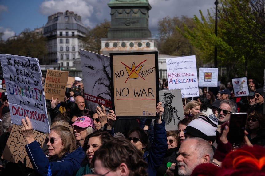 A woman holding a banner reading "No Kings, No War" takes part in the protest.