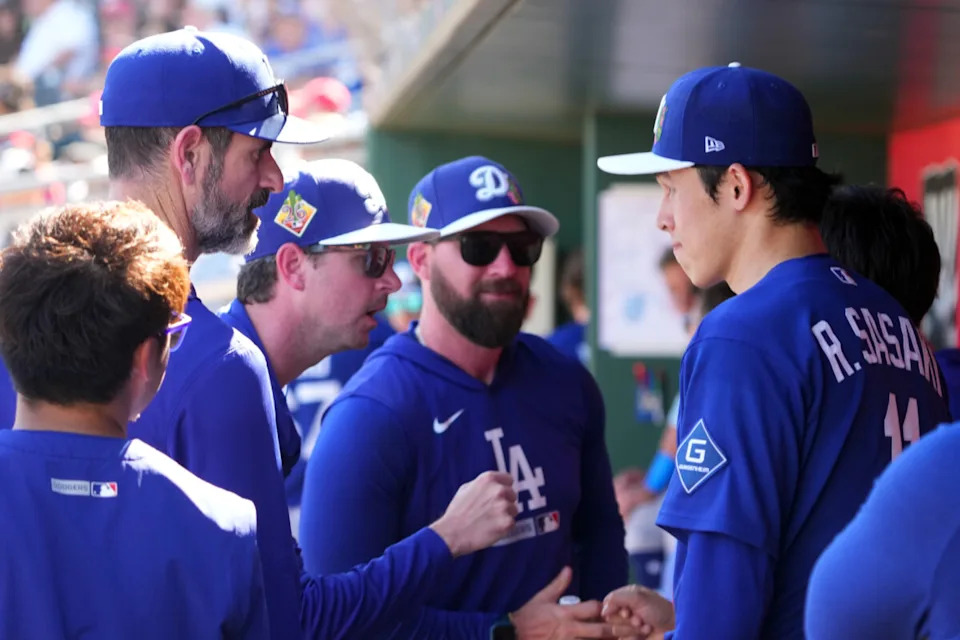Mar 3, 2026; Goodyear, Arizona, USA; Los Angeles Dodgers starting pitcher Roki Sasaki (11) talks with coaches during the fourth inning of the game against he Cleveland Guardians at Goodyear Ballpark. Mandatory Credit: Joe Camporeale-Imagn Images