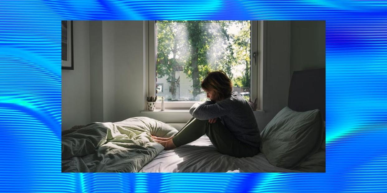 person sitting on a bed looking out a window