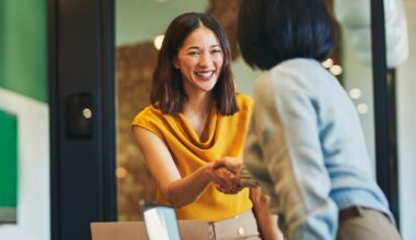 Cheerful businesswomen shaking hands in meeting room