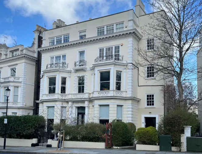 Exterior of a large, light-colored property with multiple windows and balconies, located in Holland Park.