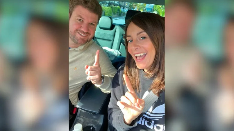 Man and woman in a car smiling widely