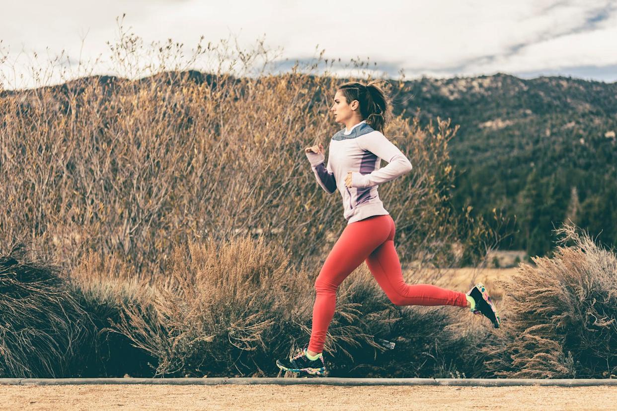 side view of female athlete running by field
