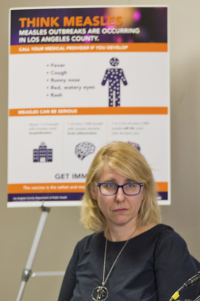 Dr. Sharon Balter in front of a "Think Measles" poster.